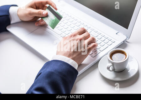 Man mano la digitazione sulla tastiera del laptop tenendo la carta di credito, close-up di shopping online. Foto Stock