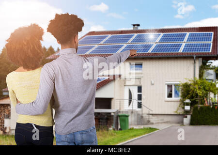 Vista posteriore di una giovane coppia in piedi di fronte a casa Foto Stock