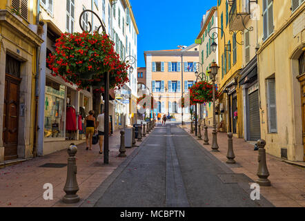 La gente camminare sulla strada stretta decorato con fiori nella città vecchia di Antibes, Francia. Foto Stock