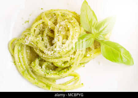 Il cibo italiano spaghetti. Spaghetti fatti in casa con il pesto e le foglie di basilico sul tavolo con la luce del sole sullo sfondo. Aria luce delicata immagine artistica. Foto Stock