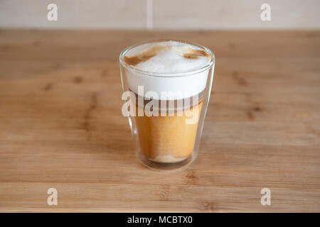 Multistrato di caffè o cappuccino in un bicchiere di vetro su un tavolo di legno. Foto Stock