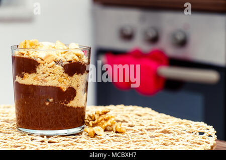 Deliziosi dessert con banana e biscotti budino di cioccolato in tazza di vetro su sfondo tabella Foto Stock