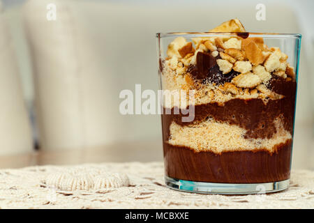 Deliziosi dessert con banana e biscotti budino di cioccolato in tazza di vetro su sfondo tabella Foto Stock