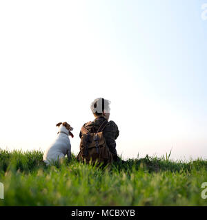 Adolescente sul prato verde con un piccolo cane bianco Foto Stock