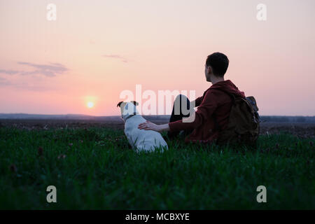 Adolescente sul prato verde con un piccolo cane bianco Foto Stock