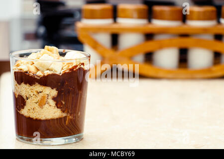 Deliziosi dessert con banana e biscotti budino di cioccolato in tazza di vetro su sfondo tabella Foto Stock