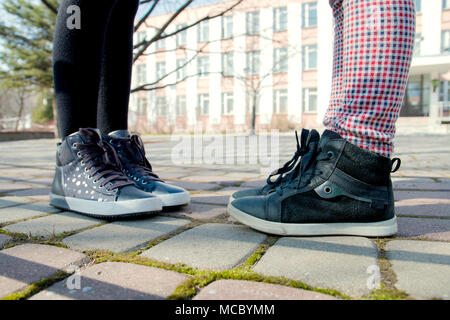 Bambini I piedi nelle scarpe di colore grigio sono opposte tra di loro sul marciapiede. Foto Stock