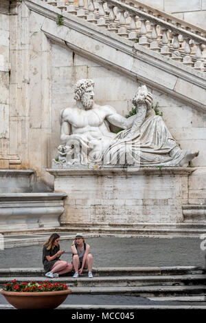 Due giovani donne turisti resto prima del Palazzo Senatorio e la scultura del Tevere a Piazza del Campidoglio al di fuori dei Musei Capitolini di Roma, Italia Foto Stock