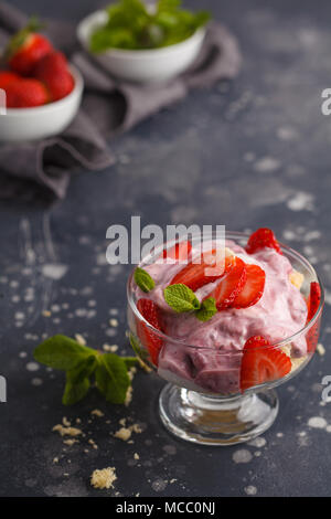 Dolce alle fragole. Berry inezia, cheesecake, parfait. Berry mousse in vetro su uno sfondo scuro. Foto Stock