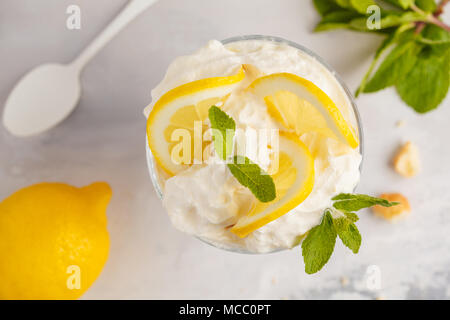 Limone dessert, limone inezia, cheesecake, panna montata, parfait. Mousse di frutta in vetro su uno sfondo luminoso. Foto Stock