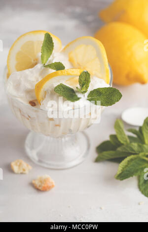 Limone dessert, limone inezia, cheesecake, panna montata, parfait. Mousse di frutta in vetro su uno sfondo luminoso. Foto Stock