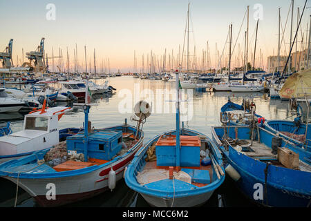 Vecchie barche da pesca e yacht moderno nel vecchio "La Cala" porto e marina a Palermo, Sicilia, Italia, mentre il sole tramonta su una giornata d'estate in agosto. Foto Stock