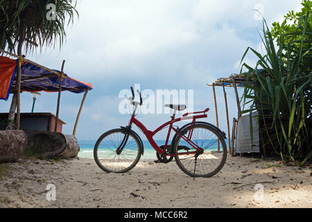 Red off-road bike sorge nella sabbia sulla spiaggia contro il mare. Intrattenimento turistico sull'isola. In sella a una moto. Luce foto oscurata. Noleggio par Foto Stock