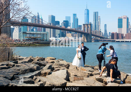 Un asiatico giovane avente video del matrimonio fatto in DUMBO Brooklyn con il ponte di Brooklyn, Jane è una giostra e dello skyline di Manhattan in background Foto Stock