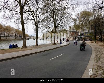 La donna a spingere un passeggino, persone bike, passeggiate e picnic lungo il Fiume Senna su una domenica pomeriggio nel Parc Rives de Seine. Parigi, Francia. Foto Stock