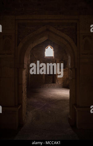 Mandu India, rovine afghano di islam unito, palazzo interno, monumento moschea musulmana e la tomba. Sunshine dalla porta nel corridoio scuro. Foto Stock