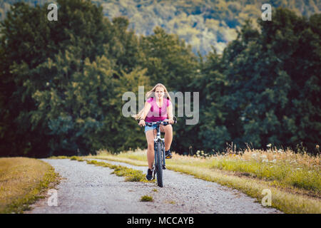 Ragazza in Bicicletta Escursioni in bicicletta verso il basso un percorso sterrato in estate Foto Stock