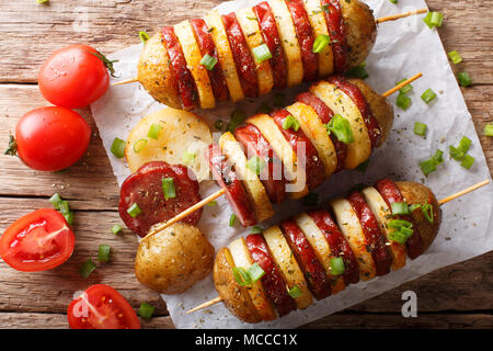 Semplice snack di spiedini di patate con salsiccia salame e cipolla verde vicino sul tavolo. Parte superiore orizzontale vista da sopra Foto Stock