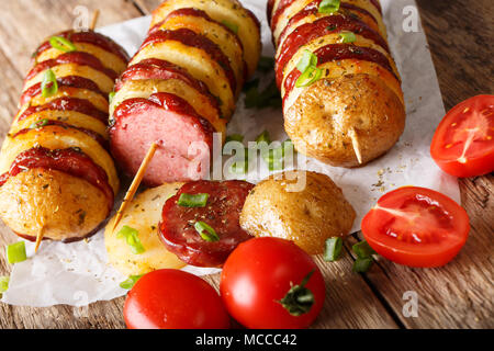 Delizioso caldo gli spiedini di patate con salsiccia il salame e i pomodori, le cipolle verdi vicino sul tavolo orizzontale. Foto Stock