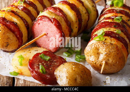 Gli spiedini di patate con salsiccia e cipolle verdi vicino sul tavolo orizzontale. Foto Stock