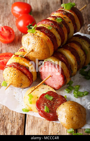 Shish kebab da patate con salsicce su spiedini di close-up su una tavola verticale. Foto Stock