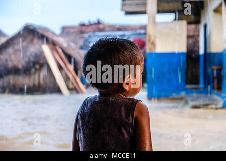 Povero ragazzo soaking wet sul giorno di pioggia da dietro - Foto Stock