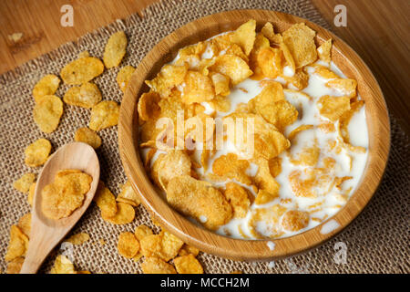 Cornflake cereali con latte in una ciotola con il cucchiaio sul tavolo, colazione veloce Foto Stock