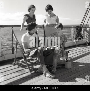 1958, storico, giovane donna e un giovane uomo sedere sulle sedie a sdraio fuori e chattare con i loro amici di sesso femminile, sul ponte di un'Unione-castello steamship guidato per la Cape in Sud Africa. Foto Stock