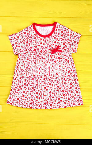 Baby-ragazza carina abito di cotone. Bambina fiori stampa casual sundress giallo su sfondo di legno. Bambini Estate Abbigliamento in vendita. Foto Stock