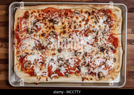 Sopra la testa fotografia di un in casa Red pizza che è stata cotta con fette di pomodoro e pancetta e funghi. Foto Stock