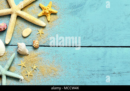 Estate mare sullo sfondo. Stella di mare, conchiglie e sabbia su una tavola di legno sfondo blu. Foto Stock