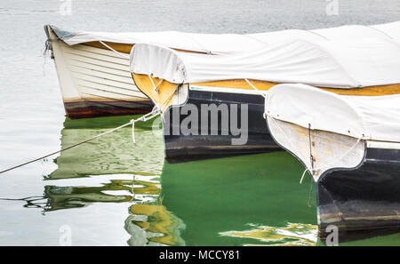 3 piccole barche a vela ricoperto con tela tarps nell'acqua in corrispondenza del Baltimore Inner Harbour con riflessi colorati Foto Stock