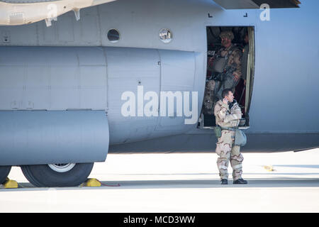 Papa Army Airfield, N.C. - Un aviatore sulla rampa verde qui comunica via radio con i compagni di aviatori sulla rampa come ottantaduesima Airborne Division Soldier pannelli a C-130J Hercules Febbraio 9, 2018 durante un giunto grande pacchetto Settimana di emergenza e Deployment Readiness esercizio Feb. 5-11. Entrambi sono indossando la missione orientata postura di protezione ingranaggio, provare la capacità di sopravvivere e di funzionare o ATSO, procedure durante l'esercizio. Avieri in 43d Aria Mobilità Operations Group ha partecipato alla formazione come bene, fornendo supporto da terra per visitare Air Force personale di volo airlifting ottantaduesima Airborne Division soldati Foto Stock