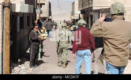 Un soldato assegnato alla xi Armored reggimento di cavalleria, National Training Center Guide iscritti della Killeen e Harker Heights Camere di Commercio attraverso una simulazione di luogo di mercato della città fittizia di Razish a Fort Irwin, California, 18 febbraio, 2018. Il Killeen e Harker Heights Camere di Commercio visita NTC è progettata per rafforzare le relazioni tra i dirigenti civili nel circostante Fort Hood comunità e i membri del servizio assegnato a Fort Hood, Texas. (US Army foto di magg. Anthony Clas, 7 Mobile degli affari pubblici distacco) Foto Stock