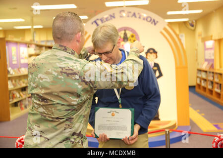 Il comando Sgt. Il Mag. Sarà Holland, comando sergente maggiore degli STATI UNITI Army Garrison Giappone, awards James Lacombe, di vigilanza bibliotecario al Camp Zama, libreria con i Comandanti di un premio per il servizio civile di Febbraio 22, 2018 durante la grande cerimonia di apertura della biblioteca stazione teen. (U.S. Foto dell'esercito di Lance D. Davis) Foto Stock