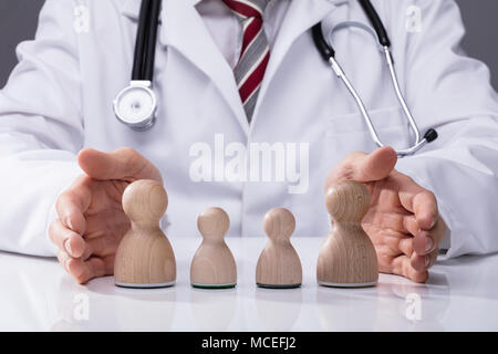 Close-up di un medico a mano in legno di protezione famiglia sulla scrivania Foto Stock