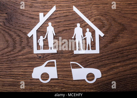 Libro bianco spaccato di una famiglia diviso con auto su sfondo di legno Foto Stock