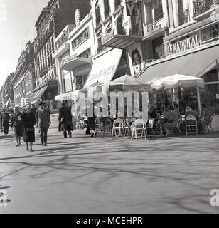 Degli anni Cinquanta, storico, primavera e parigini a piedi lungo la Avenue de Champs Elysees, Paris, Francia passato il caffè francese "Le Madrigal' Foto Stock