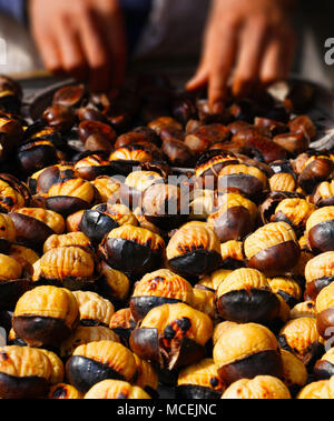 Uomo di castagne di grigliatura per la vendita su strada Foto Stock