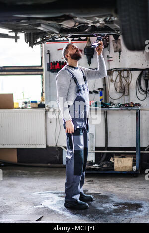 Uomo meccanico la riparazione di un auto in un garage. Foto Stock