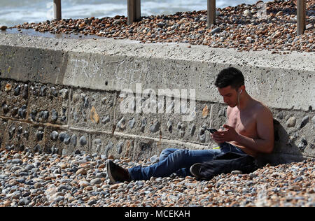 Un uomo gode di un clima caldo e sulla spiaggia di Brighton con la Gran Bretagna prevede di crogiolarvi al sole e temperature crescenti di questa settimana come il paese sembra di vedere il giorno più caldo dell'anno finora. Foto Stock