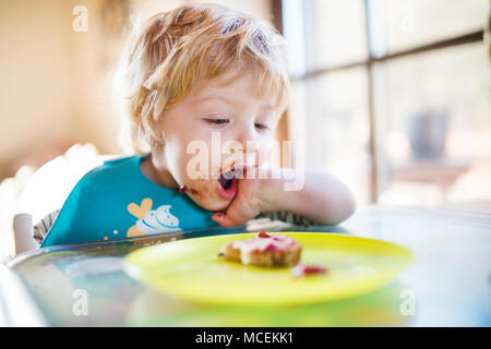 Un bimbo piccolo ragazzo di mangiare a casa. Foto Stock