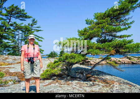 Una donna sorridente mentre in piedi su una roccia in Georgian Bay Foto Stock