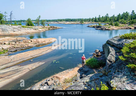 Una donna che si erge sulla sponda del Georgian Bay presso il fiume difettoso Foto Stock