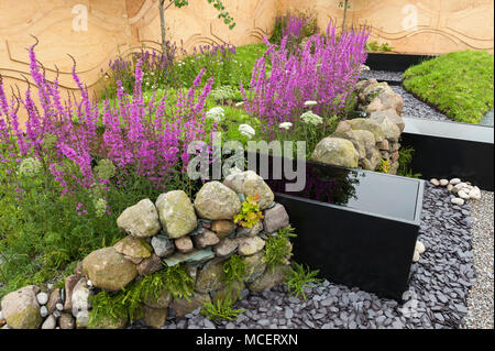 Acciaio acqua trogoli, muro di pietra, recinzione in tela, fiori colorati e ghiaia - 'acque chiare Rising l' mostrano il giardino - RHS Flower Show, Tatton Park, England, Regno Unito Foto Stock