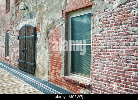 Primo piano di un edificio in mattoni con un pesante in legno, porte doppie rifilato e incernierato in ferro, uno di molti differenti architetture trovati in porto t Foto Stock