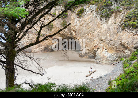 Arch Cape, Oregon - 15 Maggio 2014: la signora si siede sul lungo abbraccio al punto spiaggia vicino Cannon Beach, Oregon Foto Stock