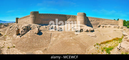 Panorama di antiche deserte adobe cittadella con massicce mura difensive, numerose torri di avvistamento e colline rocciose attorno ad esso, Rayen, Iran. Foto Stock