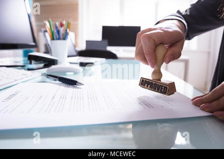 Close-up di un imprenditore di timbratura mano approvato il contratto carta in ufficio Foto Stock