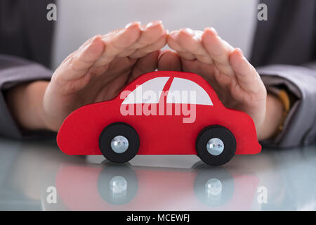 Close-up di un imprenditore della mano rosso di protezione auto in legno Foto Stock